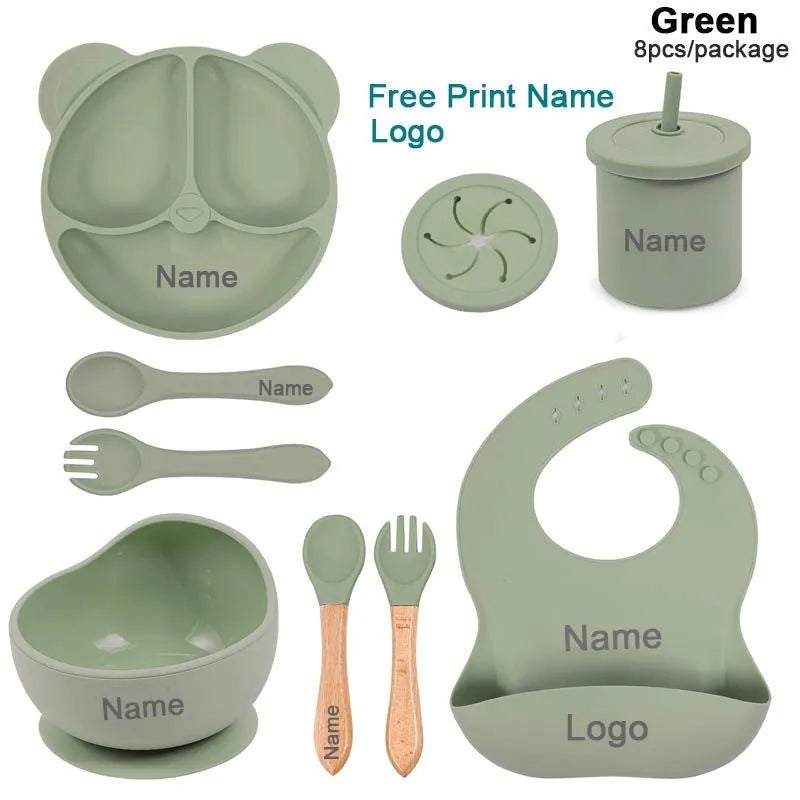 Children's silicone tableware set with cat ear cup in beige, blue and other colours on a table