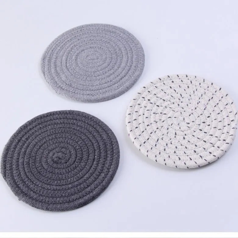 Set of three round grey cotton cord coasters, each 18 cm in diameter, on a wooden table.