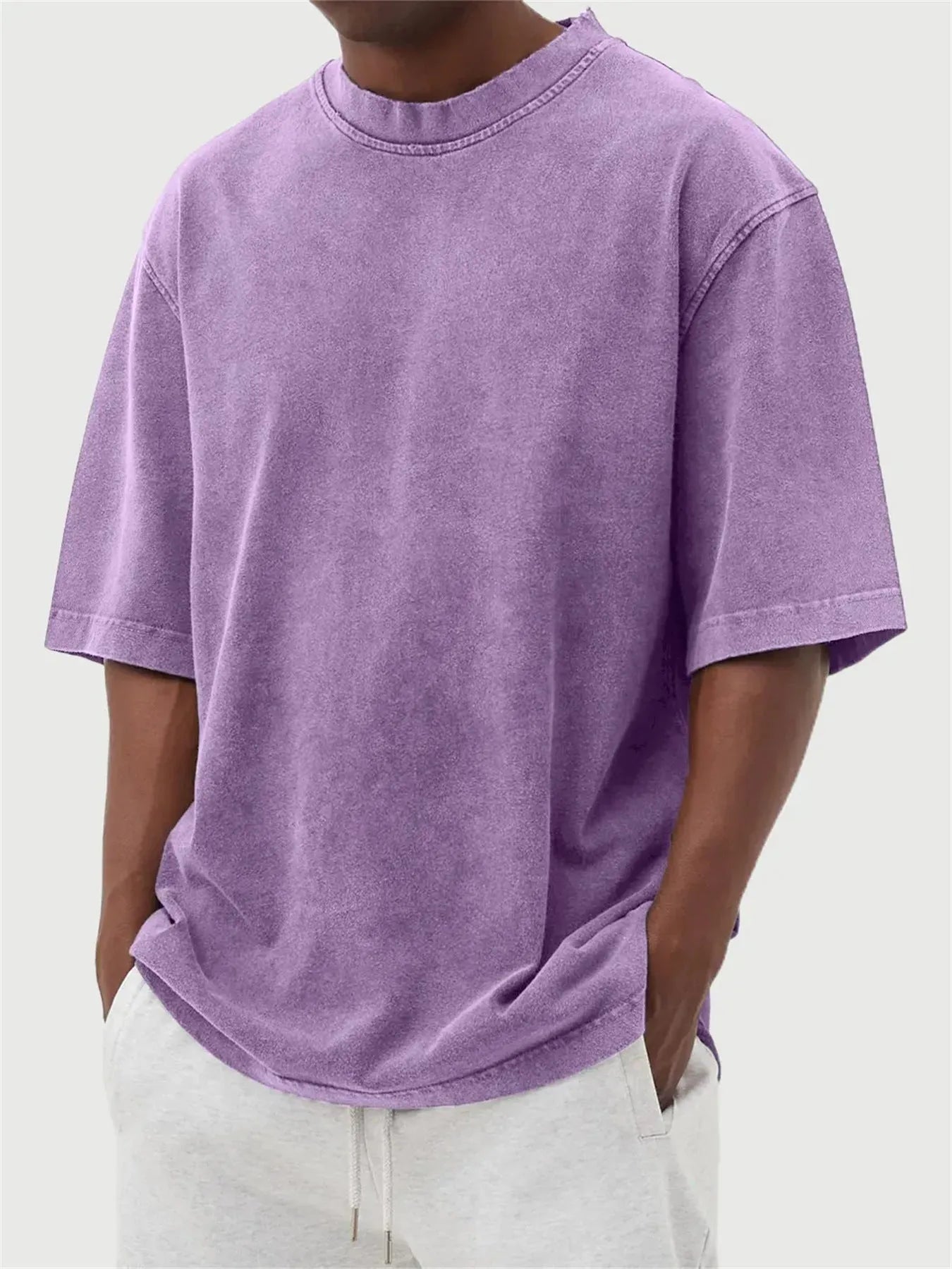 Man wearing a loose-fit, stone-washed polyester T-shirt in a solid colour with a distressed finish.
