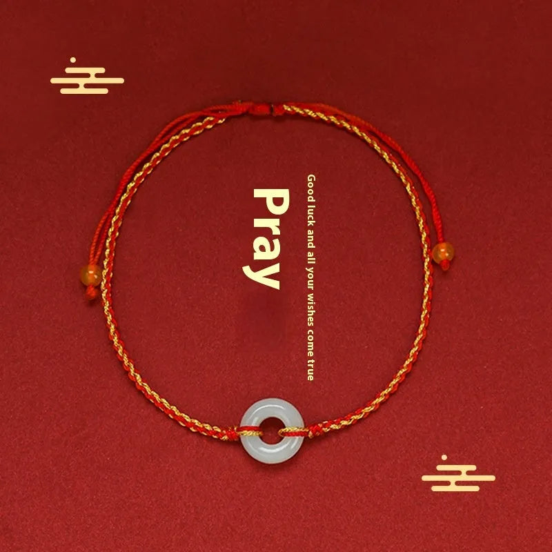 Red rope braided bracelet with natural wave-shaped Hetian jade pendant for Tiger Year birth year, on a neutral background