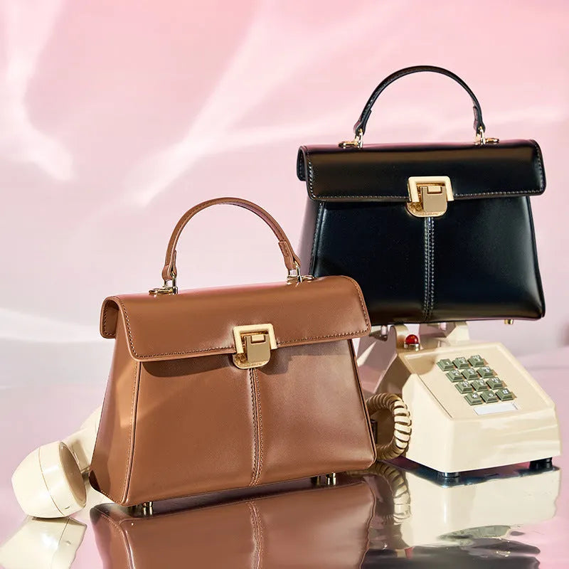 Women's black leather shoulder bag with vachette clasp, showing horizontal square shape and adjustable strap