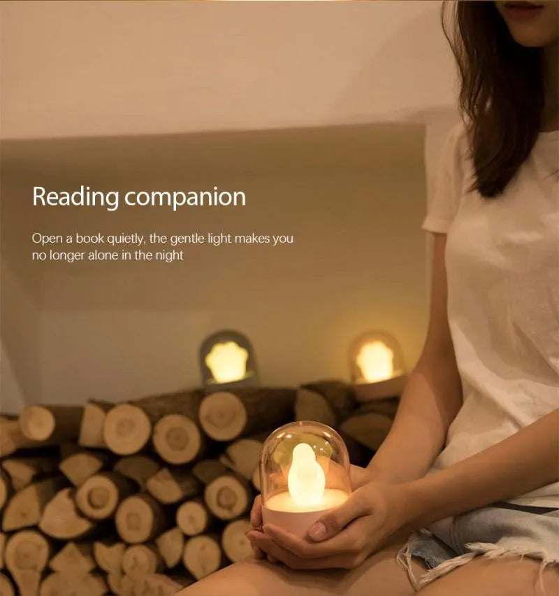 Grey cat paw shaped USB rechargeable night light and music box lamp on a desktop.