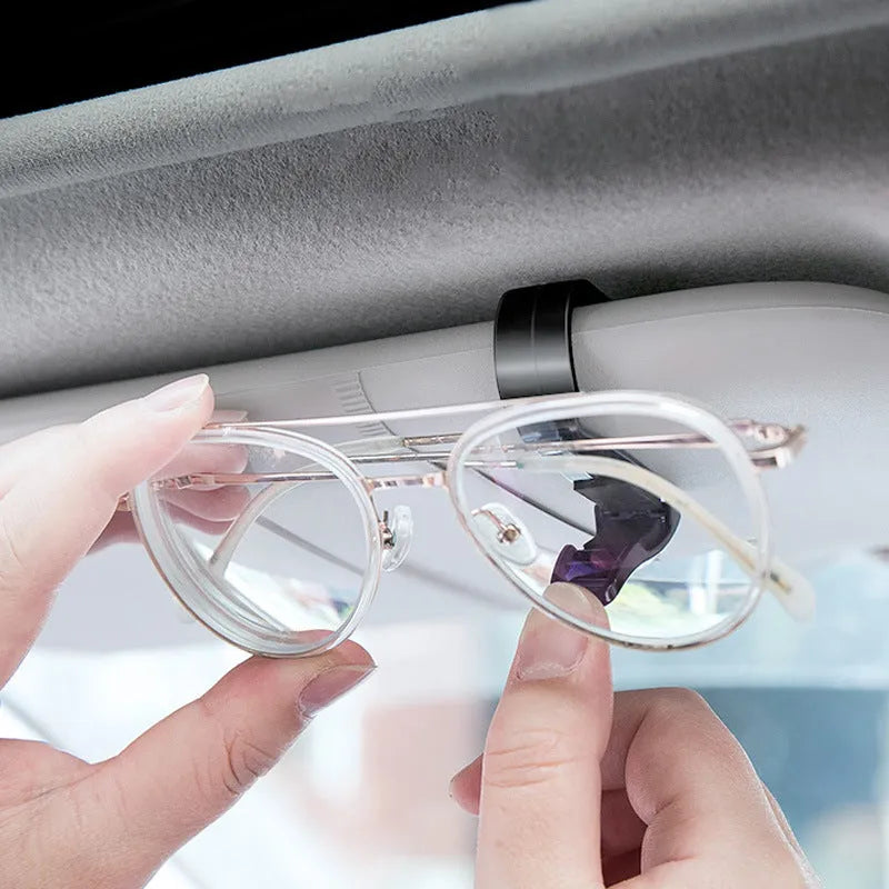Black plastic clip for holding glasses and cards on a car sunshade