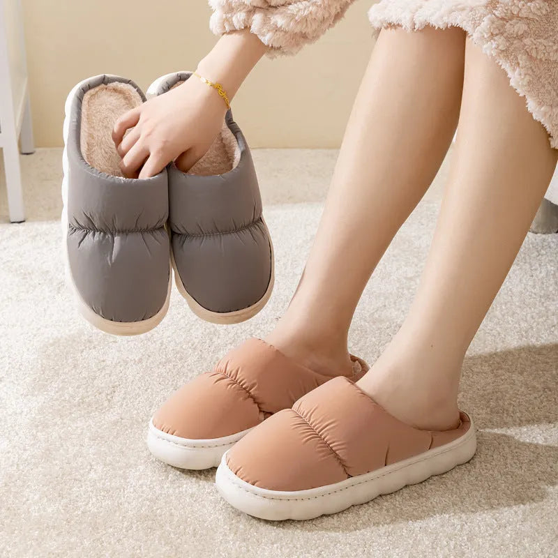Pair of thick-soled indoor slippers in blue with a wrapped toe, low heel, and artificial plush lining.
