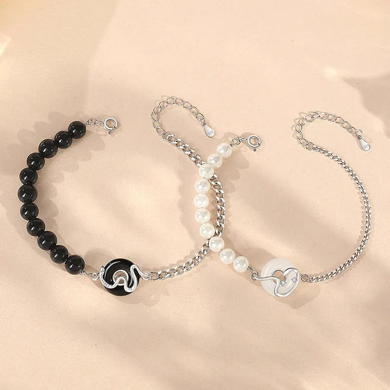 925 sterling silver bracelet with snake charm, obsidian pearl, and safe buckle closure on a wrist.