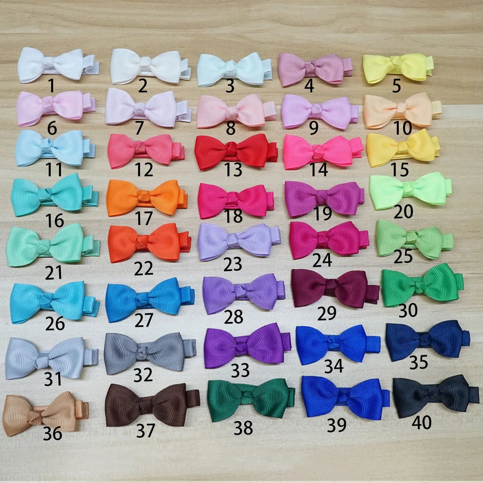 Assortment of pastel-coloured bow and barrette hair clips for babies on a white background.