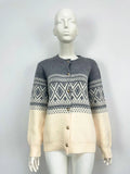 Woman wearing a grey diamond knit cardigan with contrast colour panels, long sleeves.