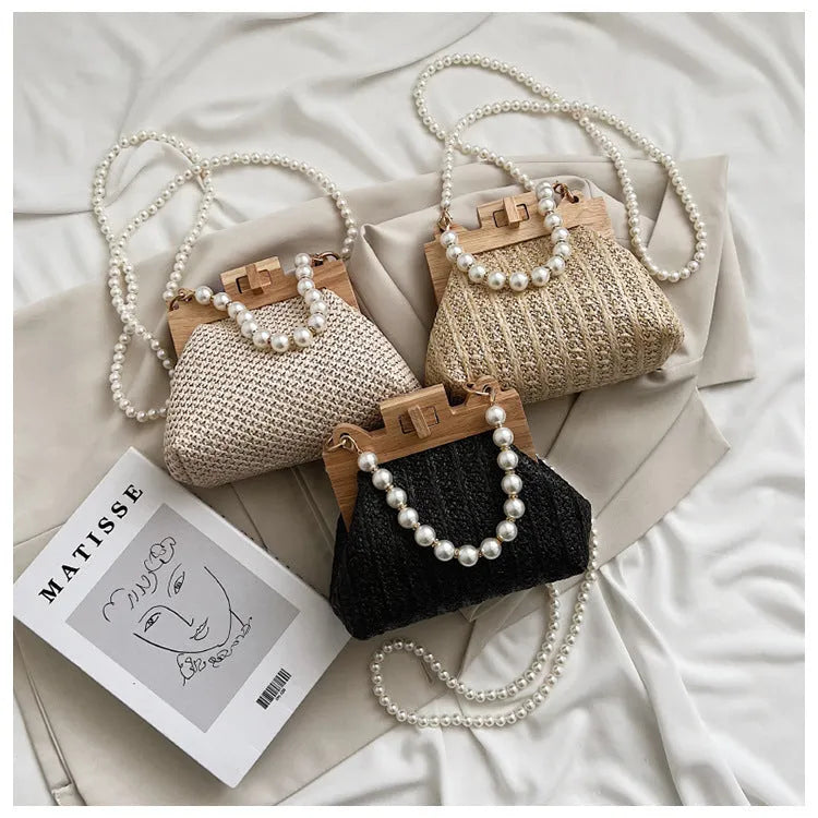 Women's woven straw shoulder bag with pearl chain detailing in horizontal square shape showing internal compartments