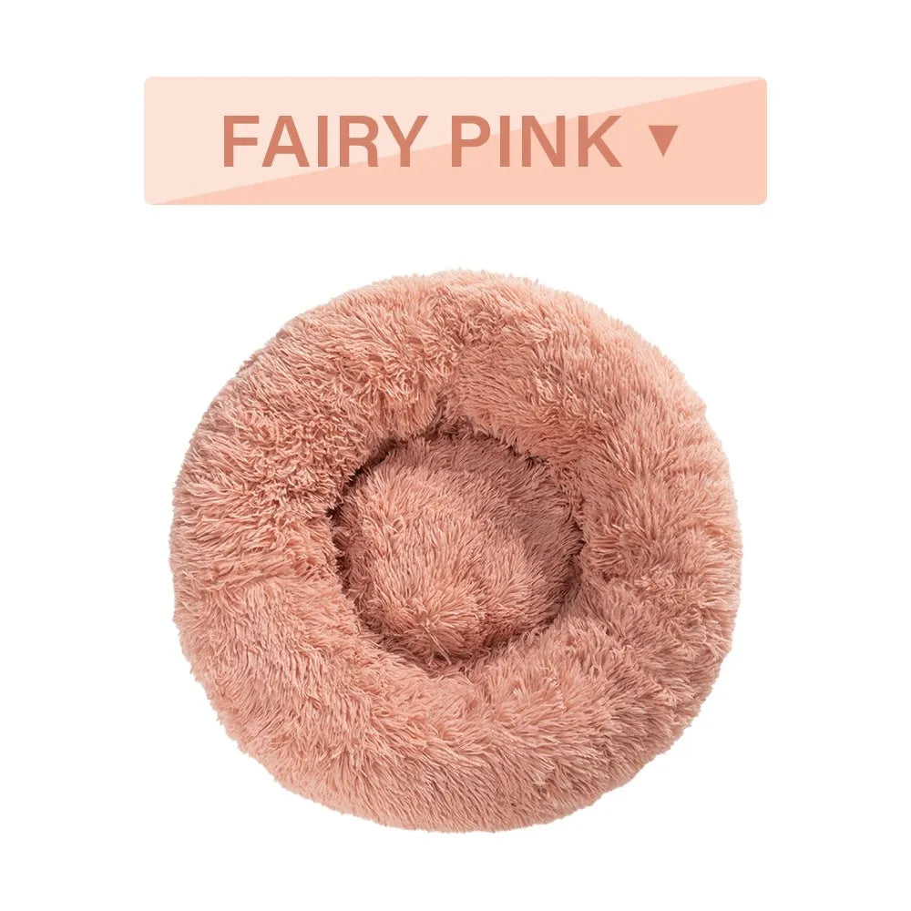 Fluffy donut-shaped dog bed in long plush material, shown in a light grey colour.
