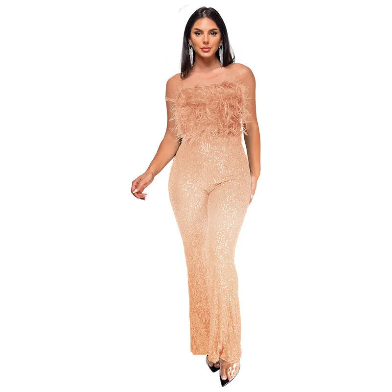 A woman wearing a black sleeveless, backless jumpsuit with sequin and feather details on the torso and flared legs.