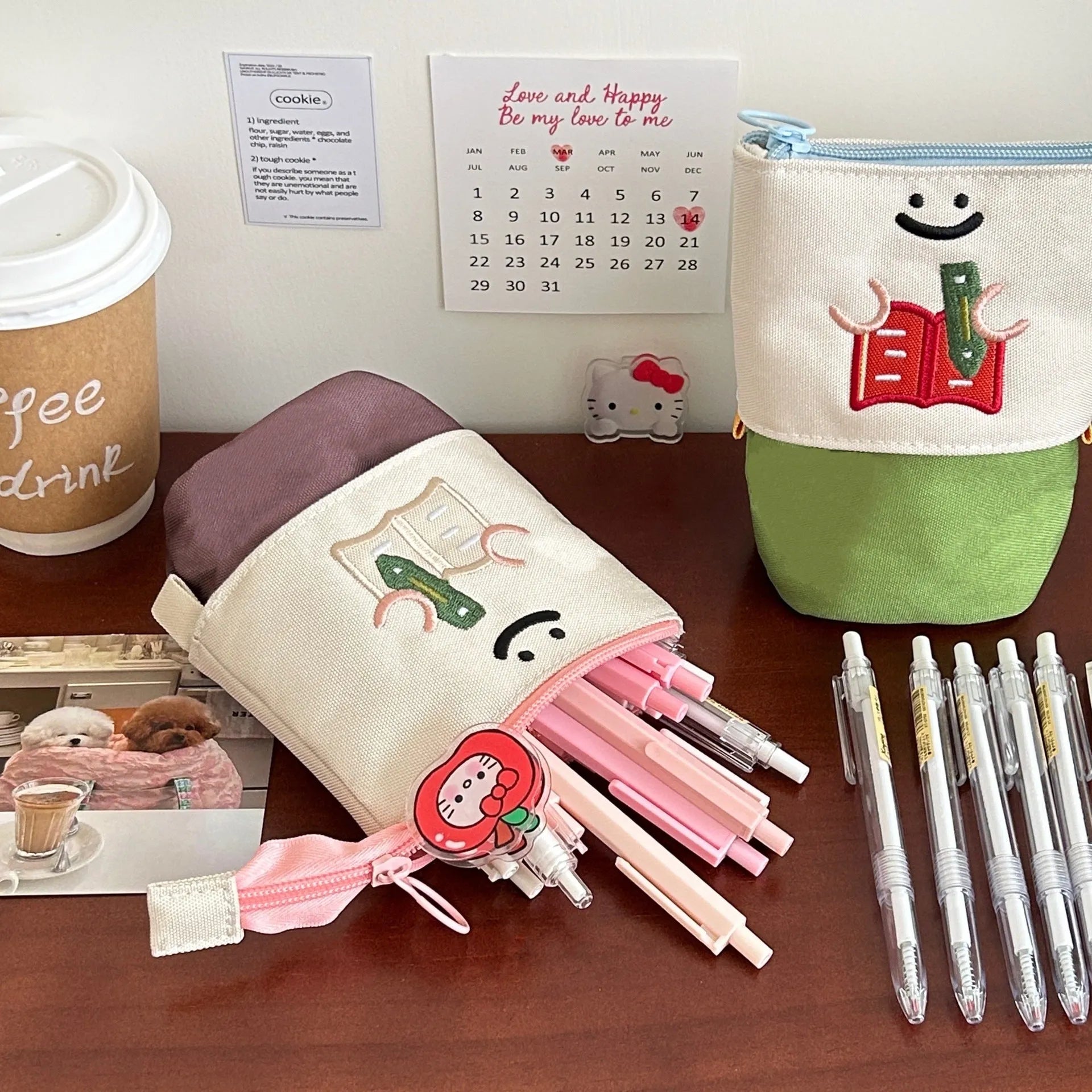 Brown collapsible Oxford cloth pencil case with zip, shown open next to pens and pencils.