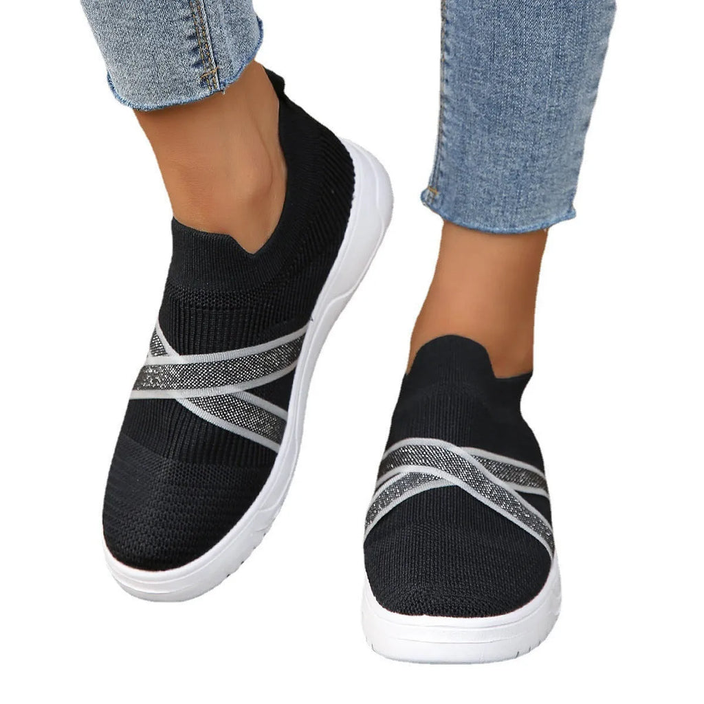 Black women's casual trainers with flyknit mesh upper, flat rubber sole, round toe, and a tassel detail.