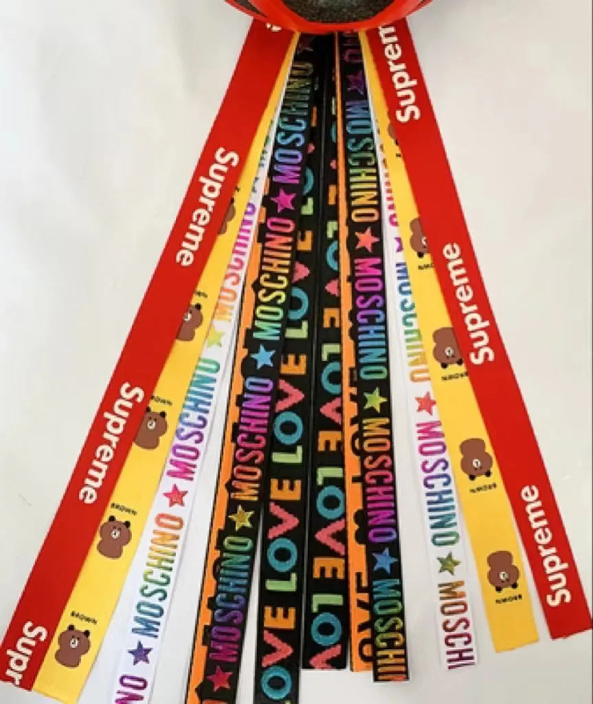 Colourful fabric helmet streamers for children's roller skating and ski helmets, shown in apricot, red, and grey.