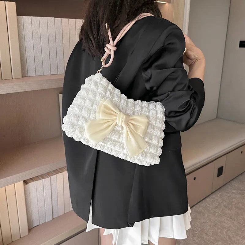 Women's horizontal square canvas handbag with single shoulder strap in black colour showing internal phone pocket