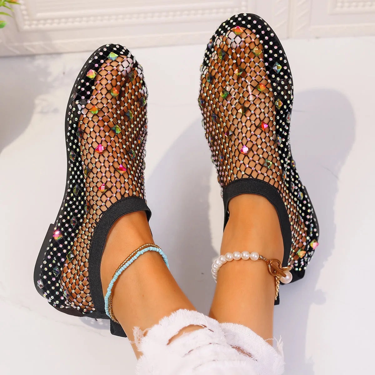 Women's flat sandals with mesh upper, colourful rhinestone decoration, and a rubber sole.