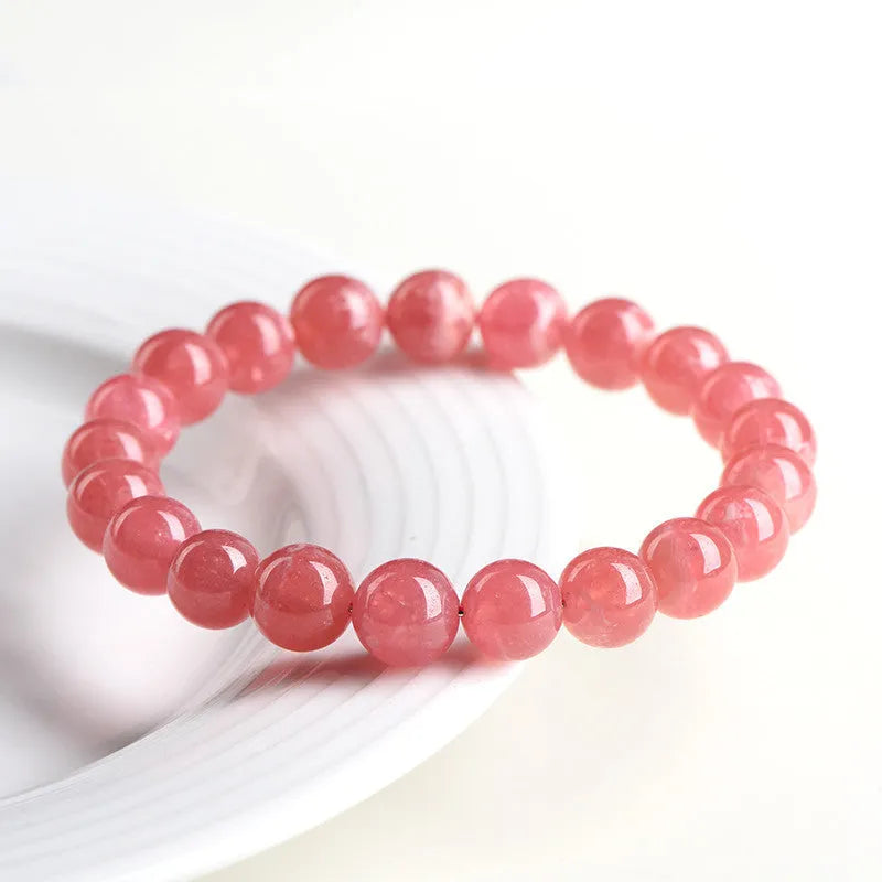 Women's red crystal bracelet with a geometric longevity lock clasp on a wrist.