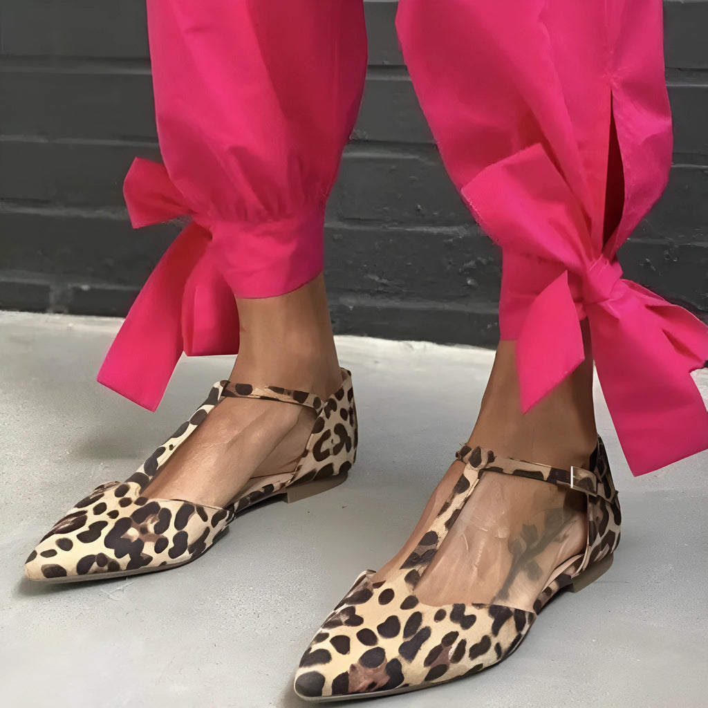 Leopard print women's pumps with a pointed toe, cross straps, and a low chunky heel on a rubber sole.