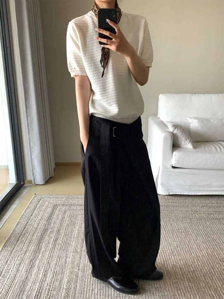 Black straight-leg Tencel cotton trousers with a single pleat and adjustable waistband on a hanger.