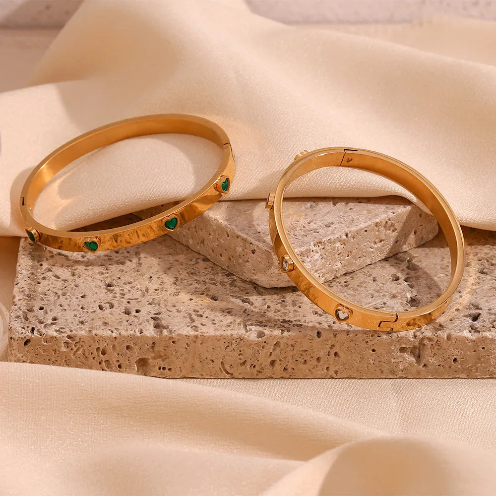 Stainless steel bracelet with a micro-inlaid peach heart charm in a golden electroplated finish.