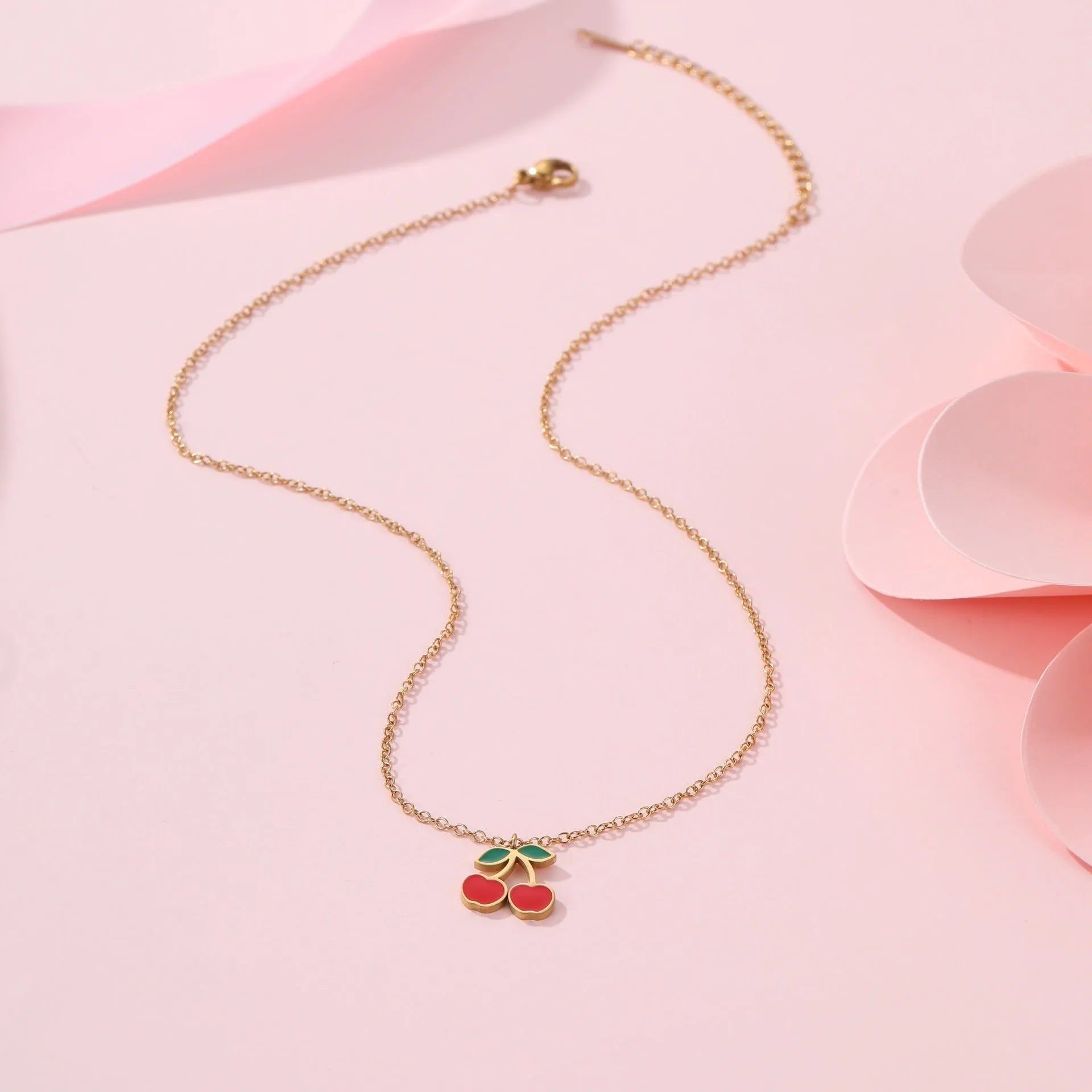 Four-piece stainless steel cherry jewellery set with gold plating: necklace, bracelet, earrings, and ring.