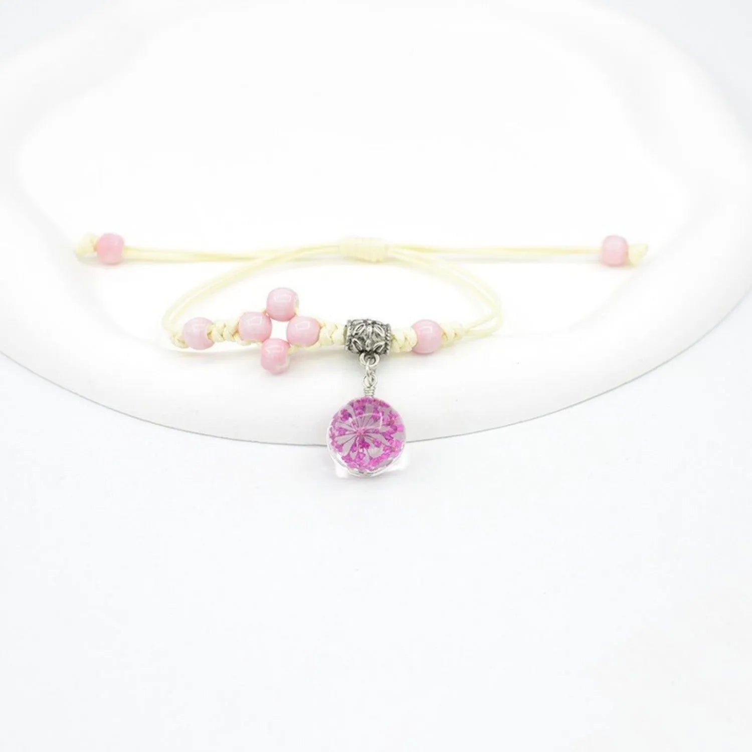 Close-up of a hand-woven glass bracelet with large beads containing real dried flowers and a lace design.