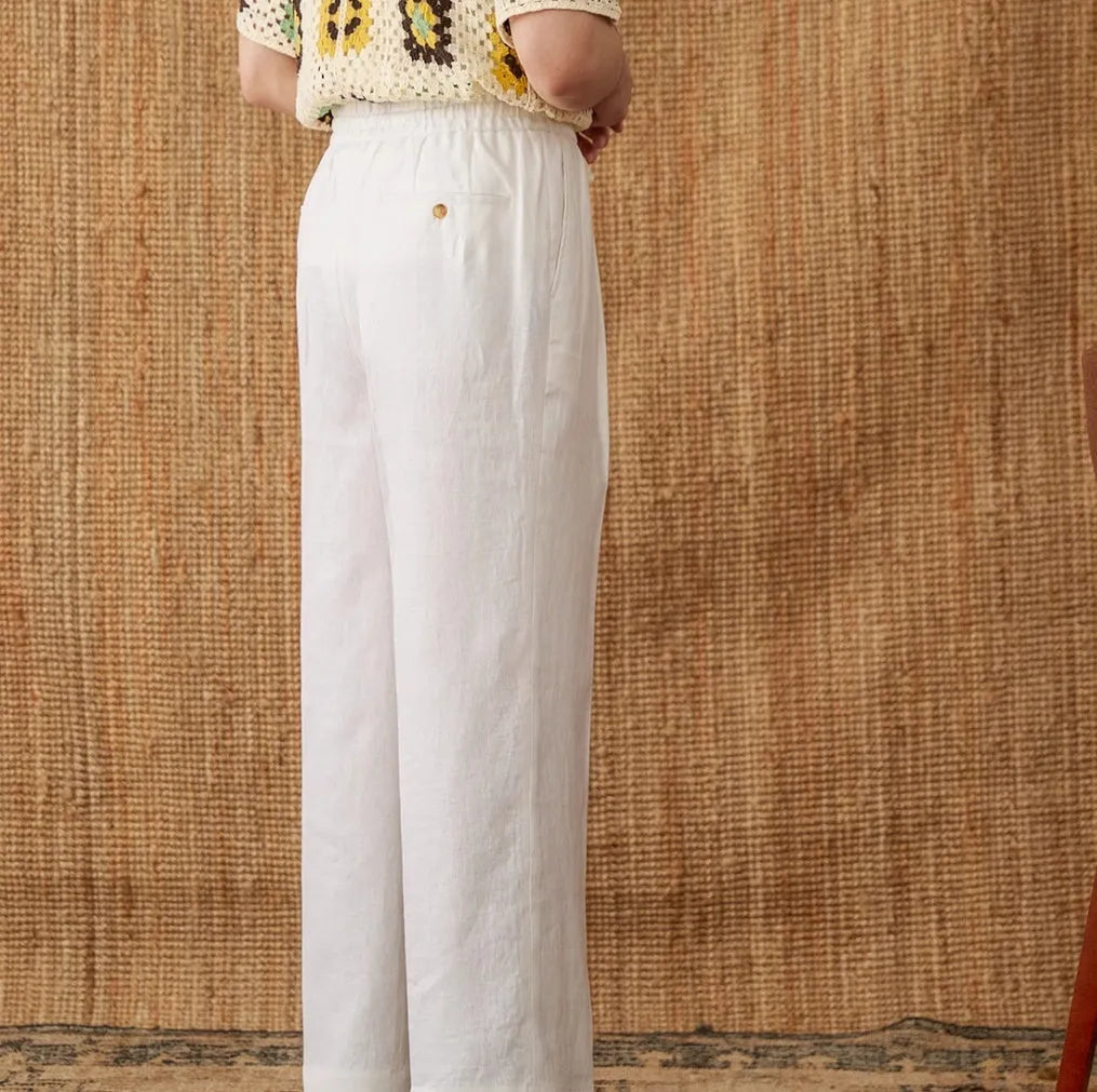Navy blue linen high-waisted trousers with an elasticated waistband and straight-leg fit on a model.