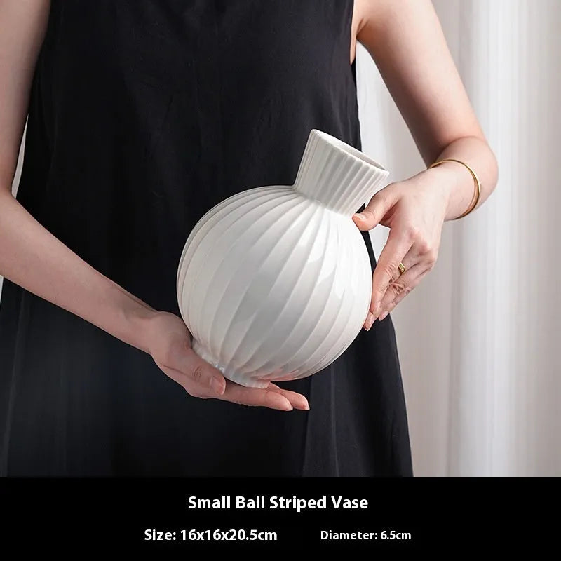 White ceramic ball vase with blue stripes on wooden table