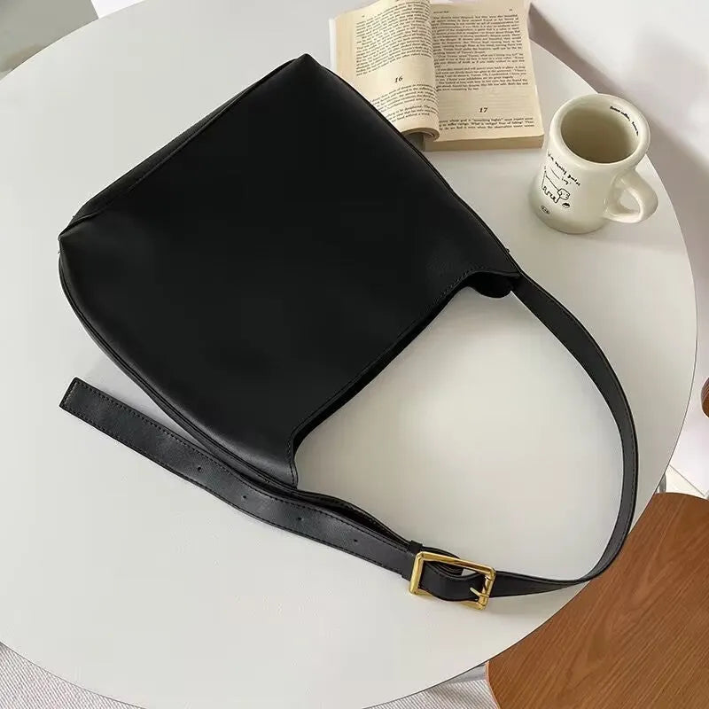 Two women's soft PU leather shoulder bags with swing threads, one black with ribbon and one brown with packet design