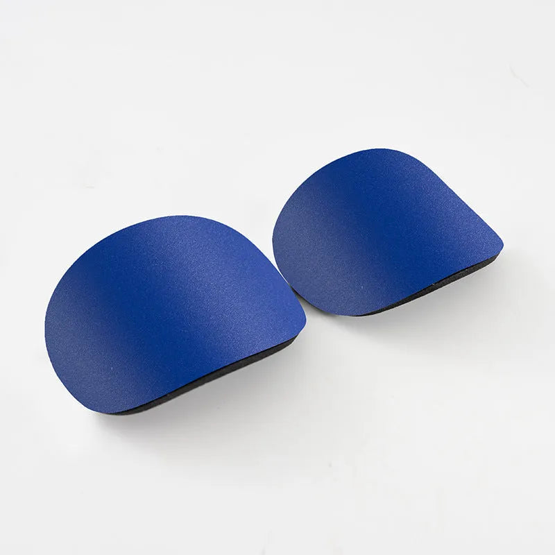 Two pairs of PU mini shin guards in black, white, red, and dream blue colours on a sports field.