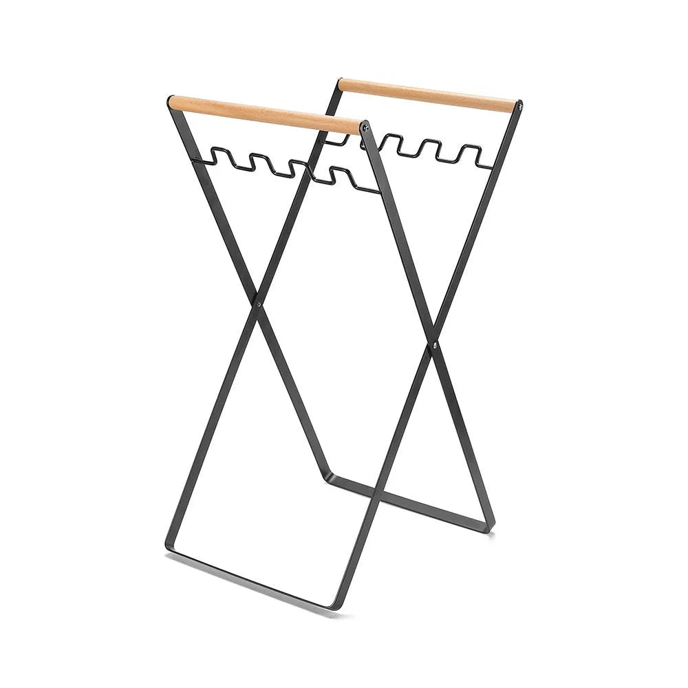 Black outdoor folding iron trash rack with a wooden handle, holding a bin bag.