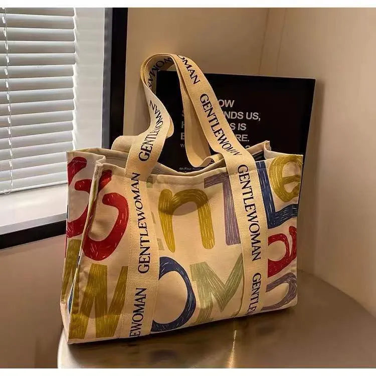 Large canvas tote bag with printed design, featuring two fabric handles, shown in available colour style options.