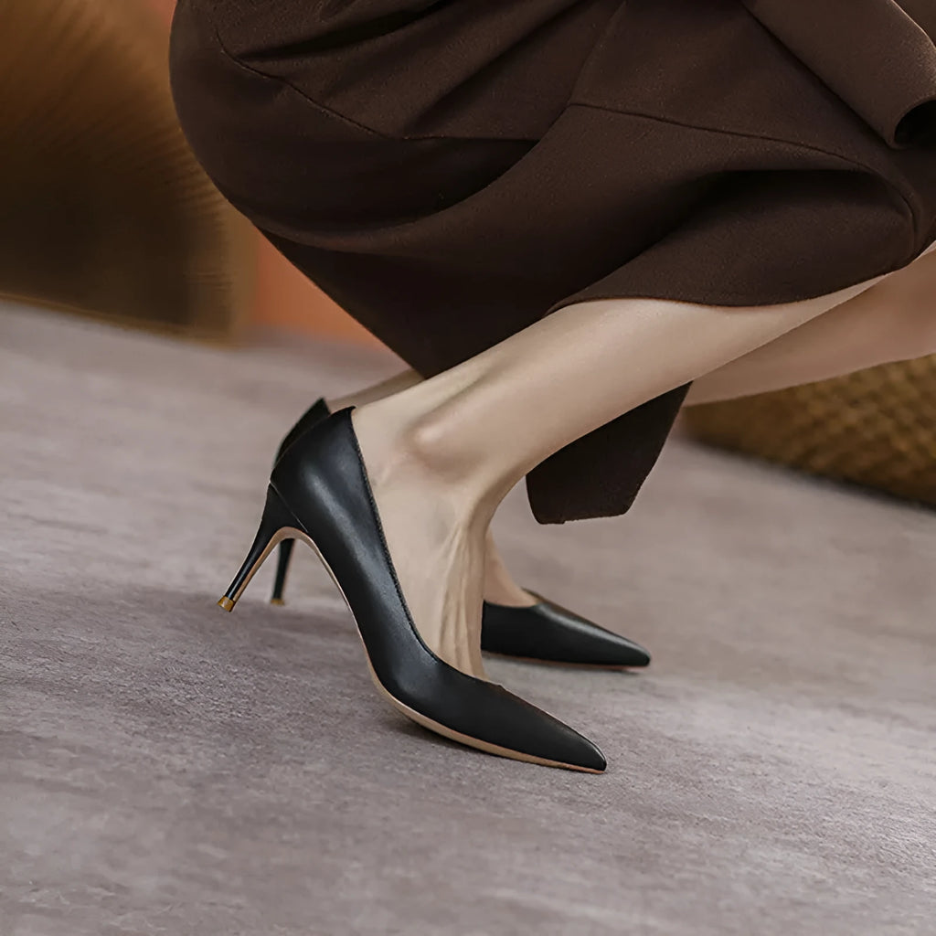 Black pointed toe stiletto high heel pump shoe with a low cut, shown on a white background.