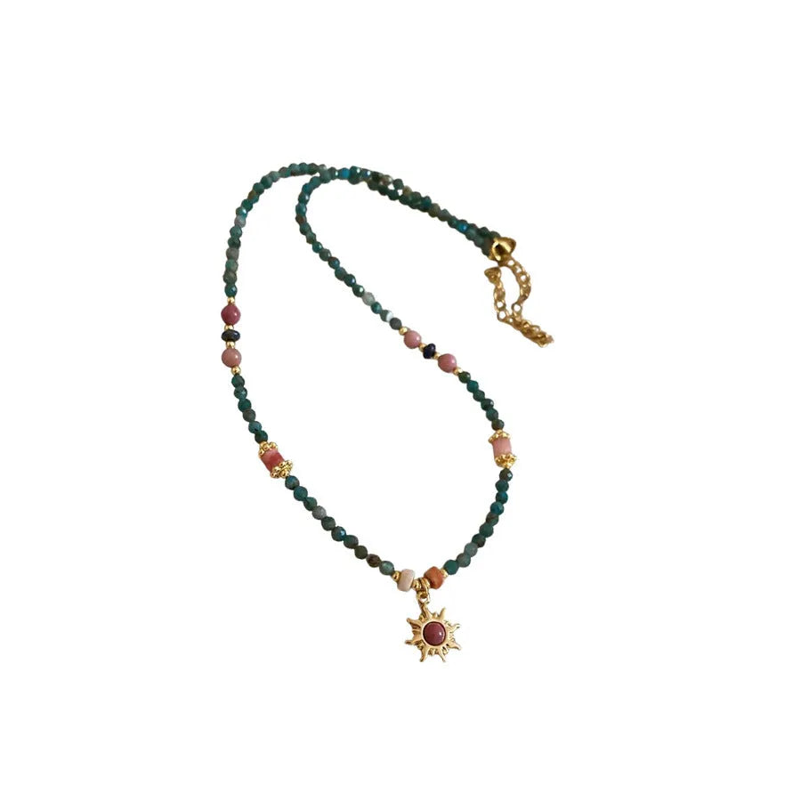 Freshwater pearl necklace with blue stone sun pendant on a gold-tone adjustable chain.