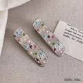 Two shiny silver metal duckbill barrettes with hollow star patterns on a plain background