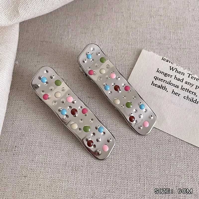 Two shiny silver metal duckbill barrettes with hollow star patterns on a plain background