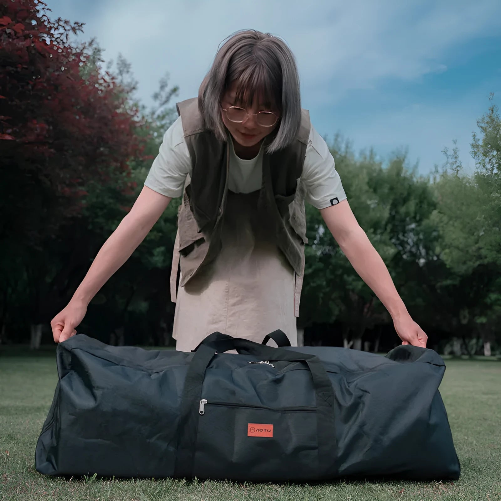 Large black waterproof storage bag for camping tables and chairs, shown folded and expanded, with 100L and 150L size options.