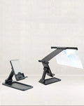 Black folding mobile phone screen magnifier with detachable holder on a desktop.