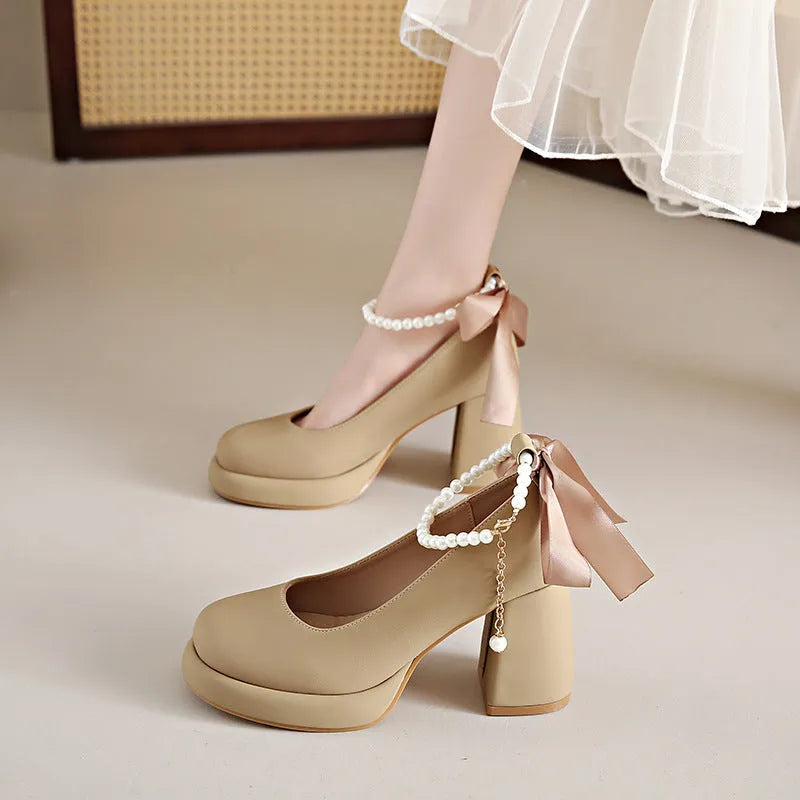 Women's beige Mary Jane shoes with a chunky block heel and an ankle-strap buckle on a round toe.