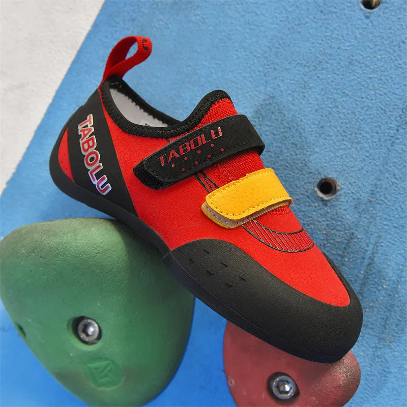 Beginner rock climbing shoes with Velcro straps and a coloured rubber sole on a climbing hold.