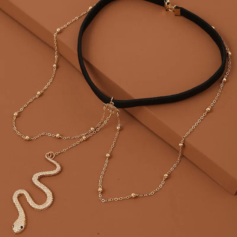 Gold metal beaded thigh chain with large snake pendant and artificial gem inlay, worn on a woman's leg