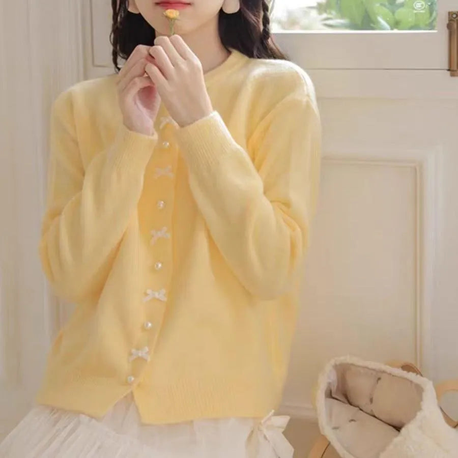 Women's solid colour cardigan sweater with bow-shaped pearl buttons on the front.