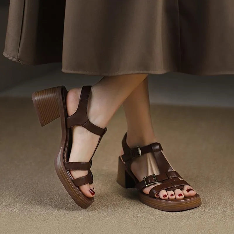 Women's black retro sandals with T-shaped buckle, chunky heel, and square open toe on a plain background.