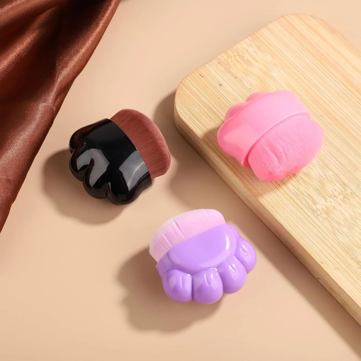Three small pet paw-shaped balm brushes with soft fibre heads and plastic storage boxes.