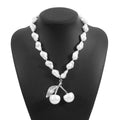 Gold and white alloy necklace with irregular cherry fruit and pearl pendant on a pearl chain.