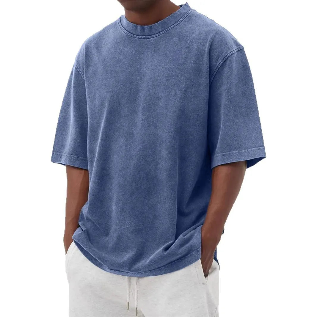 Man wearing a loose-fit, stone-washed polyester T-shirt in a solid colour with a distressed finish.