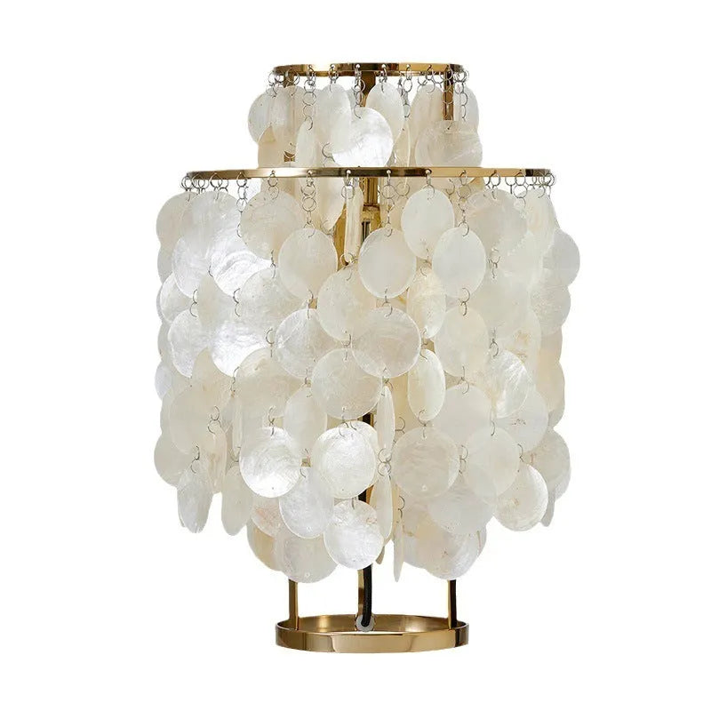 Modern bedside table lamp with a decorative white shell-shaped shade on a metallic chrome or gold base.