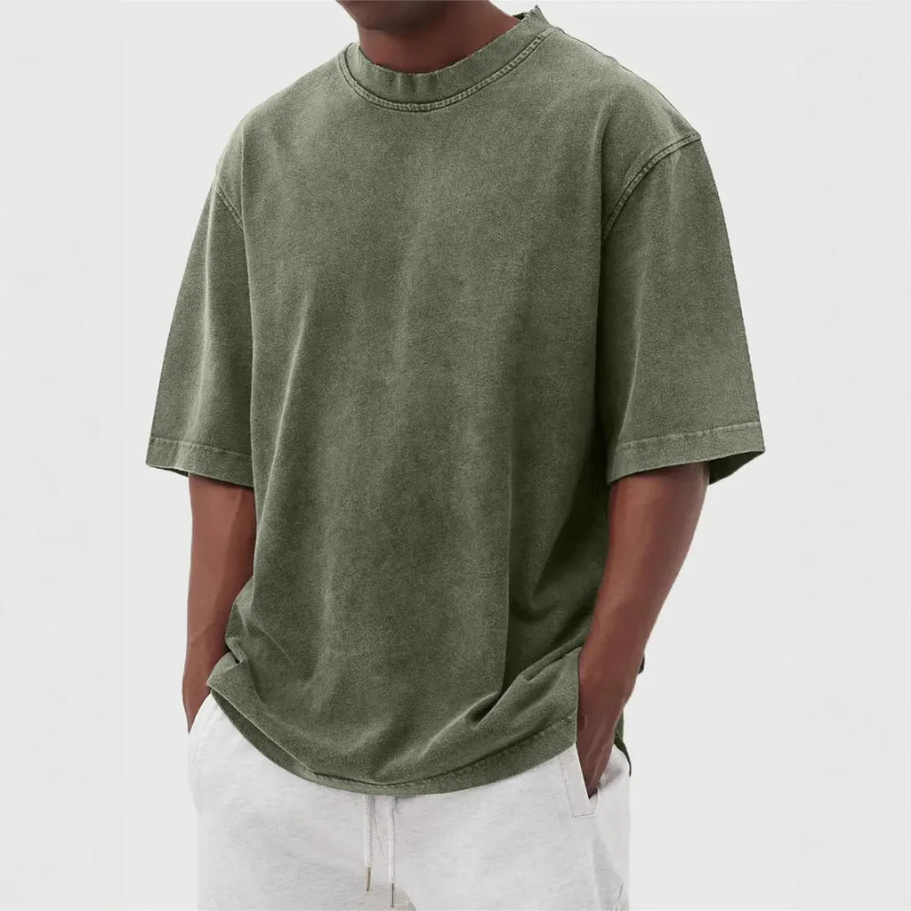 Man wearing a loose-fit, stone-washed polyester T-shirt in a solid colour with a distressed finish.