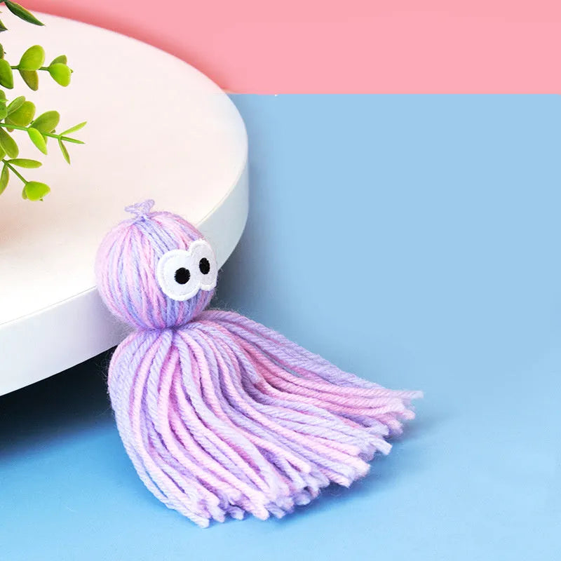 Blue grey wool ball cat toy with teaser stick, shown hanging and on a surface.