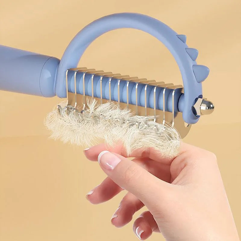 Blue dinosaur-shaped cat brush with double-sided head and self-cleaning button