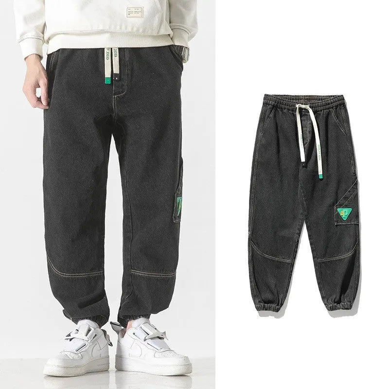 Men's loose-fit tapered cotton trousers in grey on a hanger.